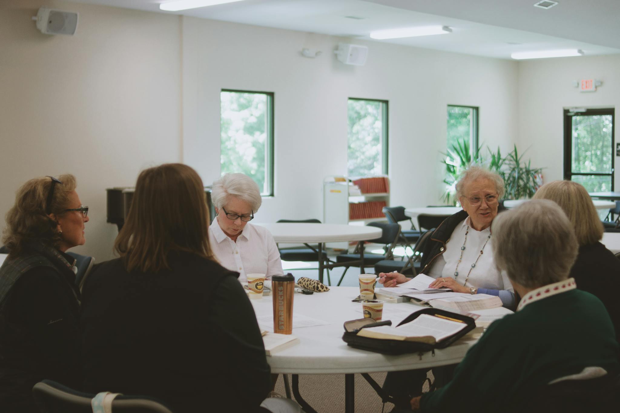 Group of women participating in a Bible study session indoors, fostering community and spiritual growth.
